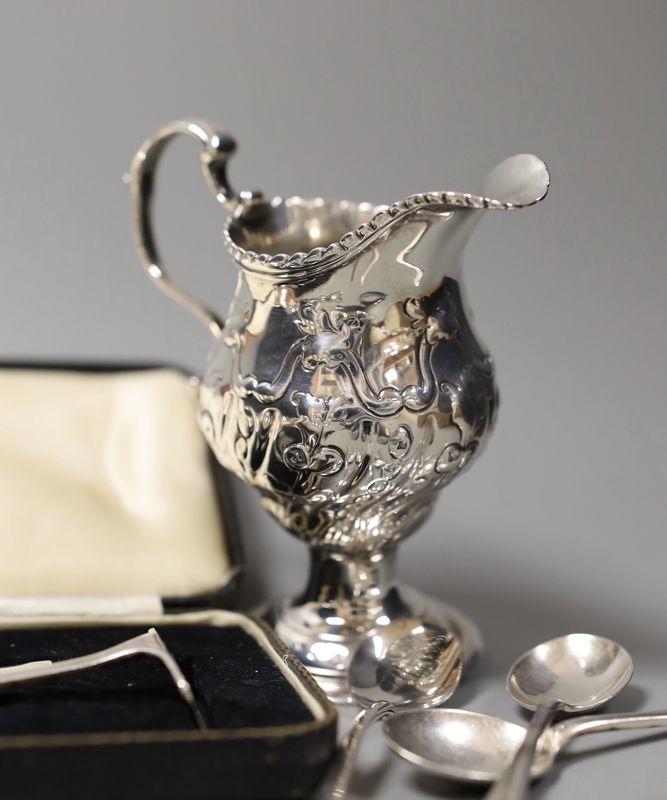 An Edwardian repousse silver oval dish, Birmingham, 1904, 22.8cm, a small quantity of assorted silver flatware including 18th and 19th century pairs of sugar nips, an 18th century silver toddy ladle, white metal cream ju